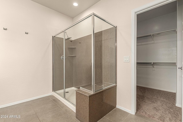 bathroom featuring baseboards, tile patterned floors, a spacious closet, and a shower stall