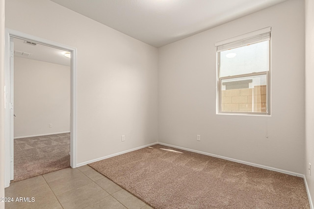 unfurnished room featuring baseboards, visible vents, and light carpet