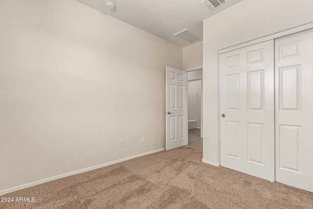 unfurnished bedroom featuring light colored carpet and a closet