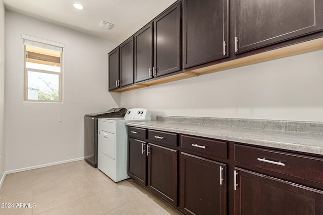 washroom with light tile patterned flooring, washing machine and clothes dryer, and cabinets