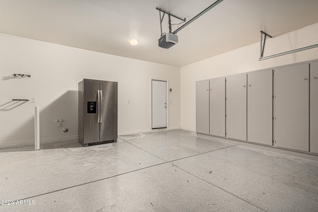 garage with a garage door opener and stainless steel fridge with ice dispenser