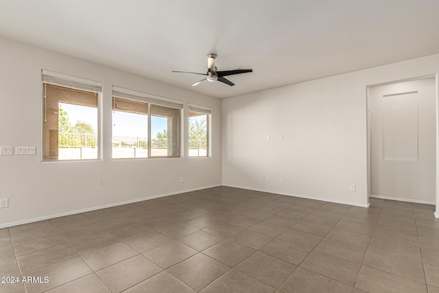 unfurnished room with tile patterned flooring, a ceiling fan, and baseboards