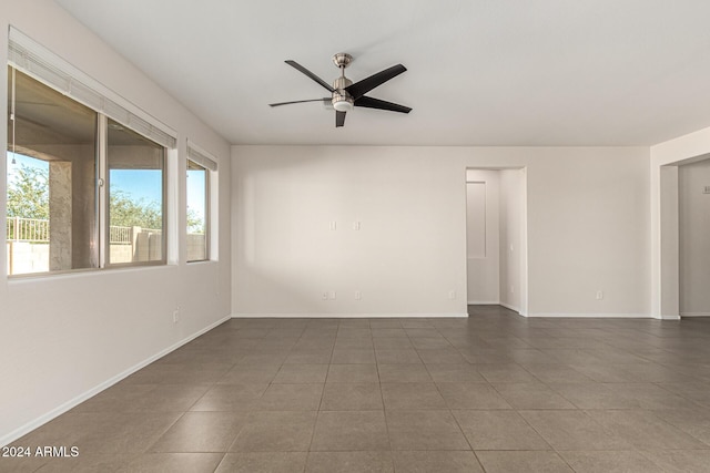 tiled spare room featuring baseboards, ceiling fan, and a healthy amount of sunlight