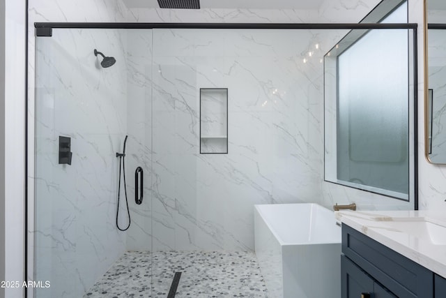 bathroom featuring a freestanding bath, a marble finish shower, and vanity