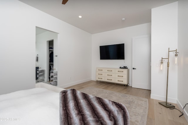 bedroom with baseboards, ceiling fan, a walk in closet, light wood-type flooring, and recessed lighting