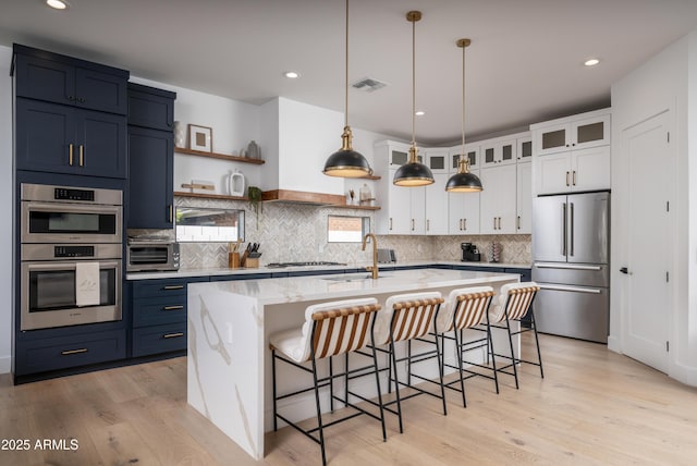 kitchen with glass insert cabinets, decorative light fixtures, stainless steel appliances, white cabinetry, and open shelves