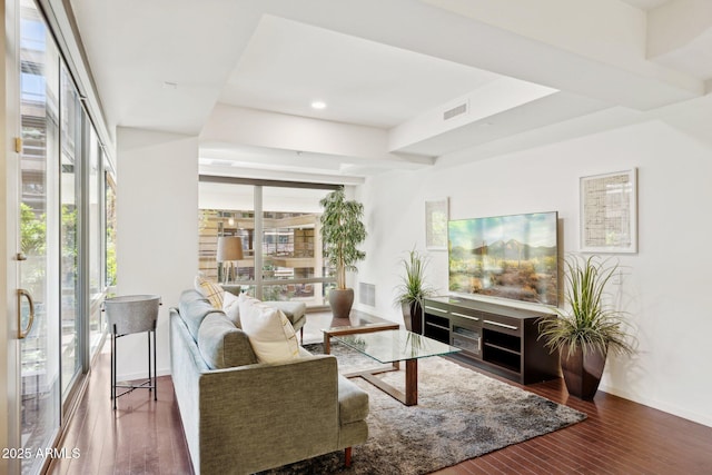 living room with wood-type flooring, visible vents, and baseboards