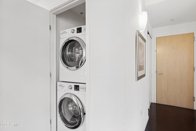 washroom with stacked washer / dryer, laundry area, and dark wood finished floors