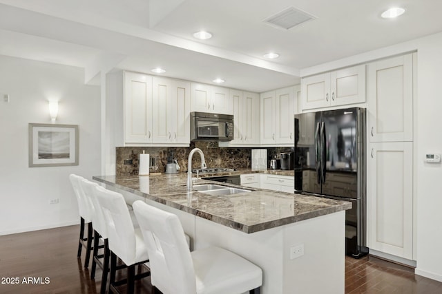 kitchen with black appliances, recessed lighting, visible vents, and a peninsula