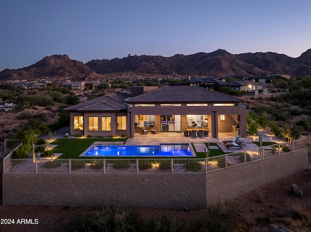 back house at dusk with a mountain view, a fenced in pool, and a patio area