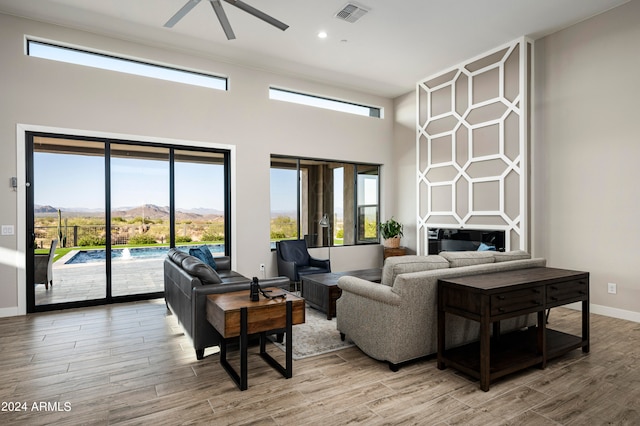 living room featuring light hardwood / wood-style flooring, ceiling fan, and plenty of natural light