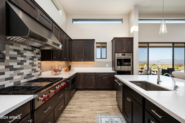 kitchen with a mountain view, sink, tasteful backsplash, light hardwood / wood-style flooring, and decorative light fixtures