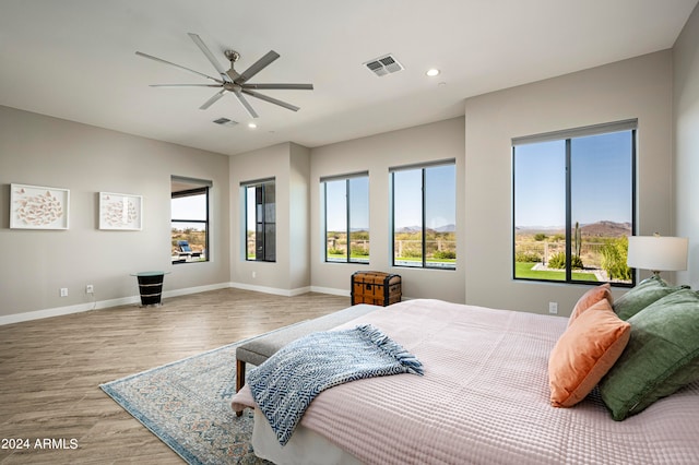 bedroom with ceiling fan, hardwood / wood-style flooring, and multiple windows