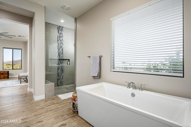 bathroom featuring plus walk in shower, wood-type flooring, and ceiling fan