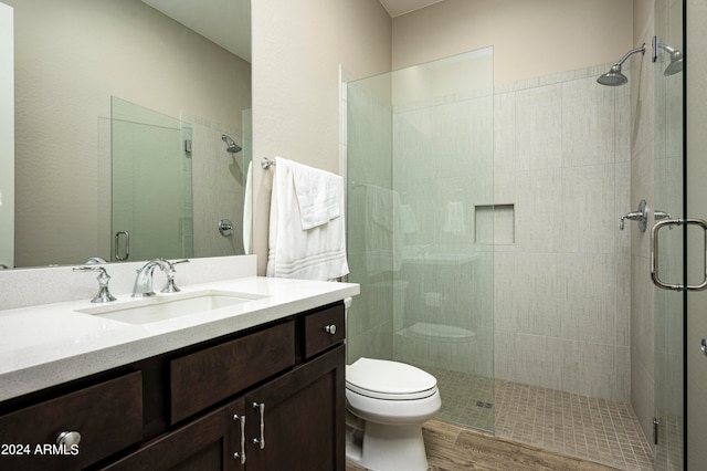 bathroom featuring a shower with shower door, vanity, toilet, and hardwood / wood-style flooring