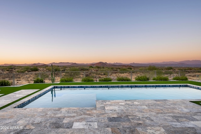 pool at dusk with a mountain view and a patio area