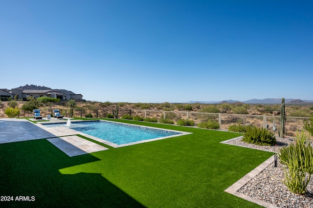 view of swimming pool with pool water feature, a mountain view, a patio area, and a yard