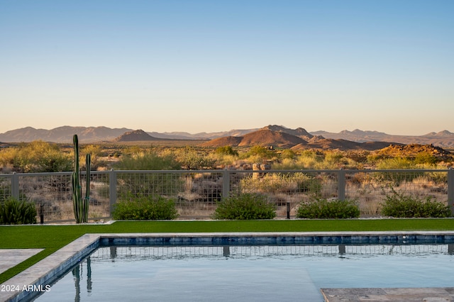 pool at dusk with a yard and a mountain view