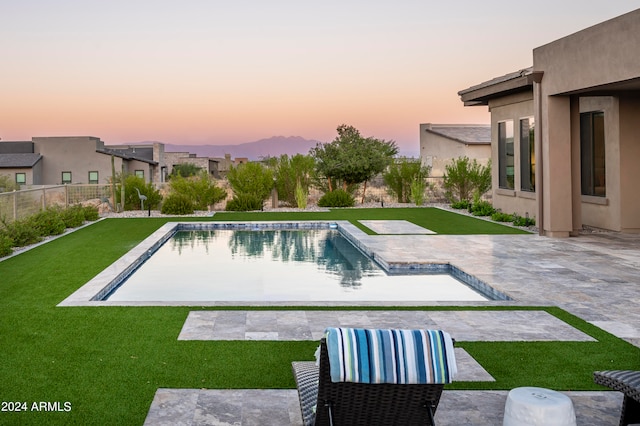 pool at dusk with a lawn and a patio area