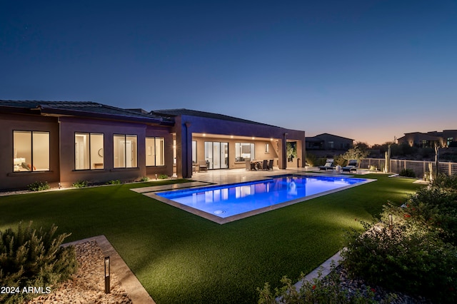 pool at dusk with a patio and a yard