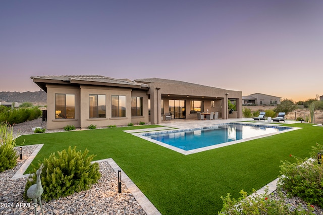 pool at dusk featuring a patio and a yard