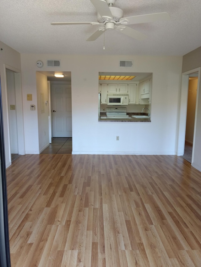 unfurnished living room with ceiling fan, sink, a textured ceiling, and light hardwood / wood-style floors