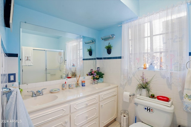 bathroom with tile walls, an enclosed shower, vanity, and toilet