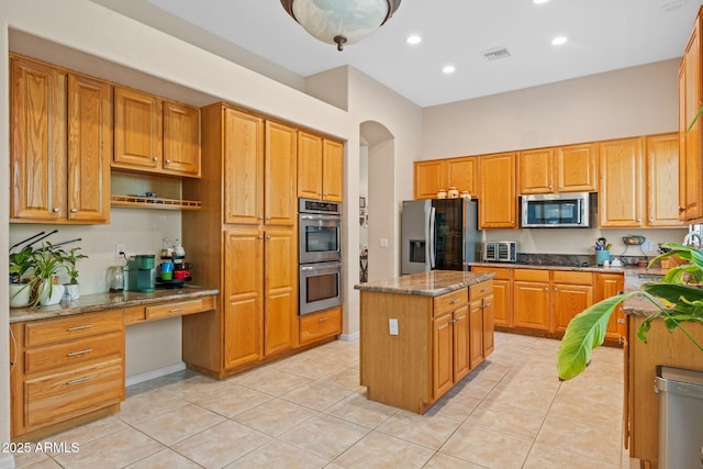 1943 E Drake Dr, Tempe, AZ 85283 - kitchen with stainless steel appliances, a center island, dark stone counters, light tile patterned floors, and arched walkways
