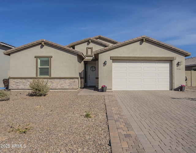 ranch-style house with decorative driveway, a tiled roof, an attached garage, and stucco siding