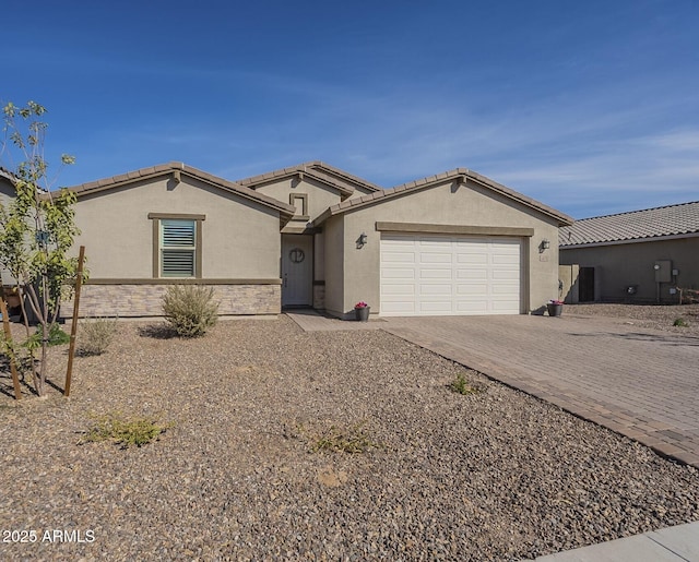 single story home with an attached garage, a tile roof, stone siding, decorative driveway, and stucco siding