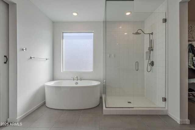 bathroom with a soaking tub, baseboards, and a stall shower