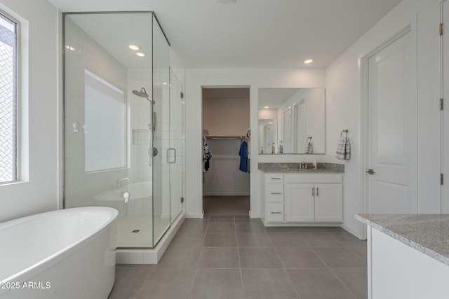 bathroom featuring a soaking tub, a shower stall, a walk in closet, and vanity