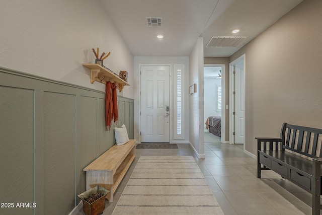 entrance foyer with wainscoting, visible vents, a decorative wall, and light tile patterned flooring