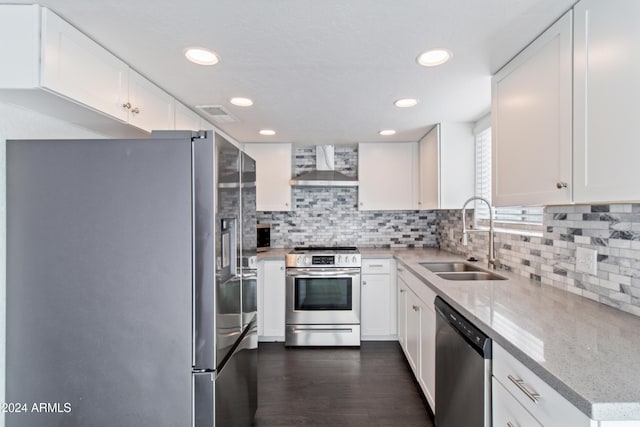 kitchen with light stone countertops, sink, wall chimney exhaust hood, stainless steel appliances, and white cabinets