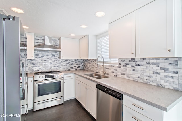 kitchen with sink, white cabinets, stainless steel appliances, and wall chimney range hood