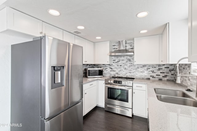 kitchen with white cabinetry, sink, stainless steel appliances, wall chimney range hood, and light stone counters