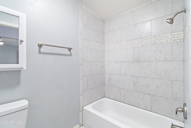 bathroom featuring tiled shower / bath combo and toilet