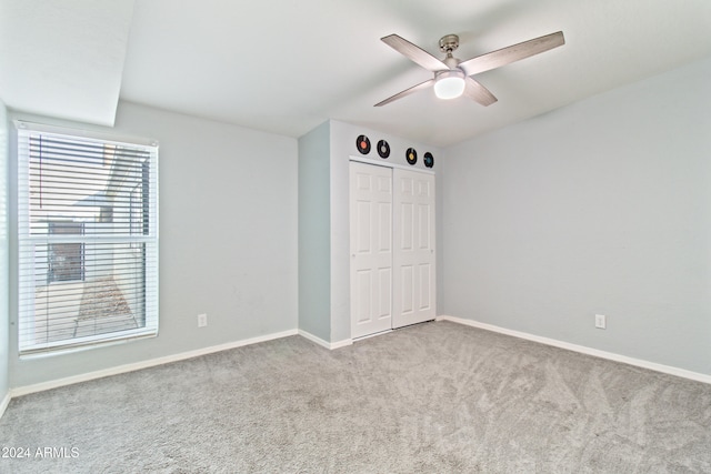 unfurnished bedroom featuring a closet, light colored carpet, and ceiling fan