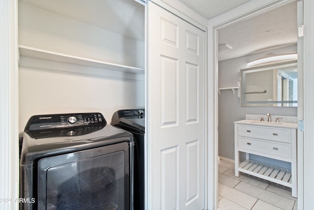 laundry area with washing machine and dryer, light tile patterned floors, and sink