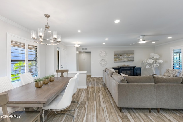 living room with ceiling fan with notable chandelier, ornamental molding, and light wood-type flooring