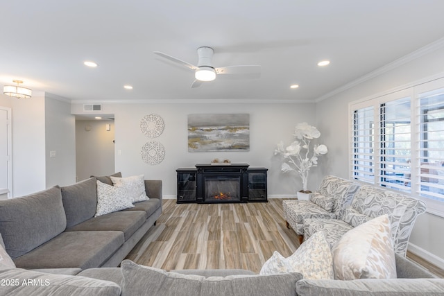 living room featuring light hardwood / wood-style flooring, ornamental molding, and ceiling fan