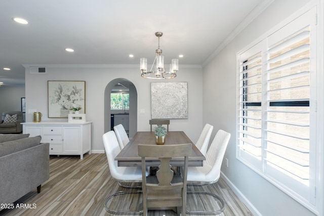 dining space featuring crown molding, a chandelier, and light wood-type flooring