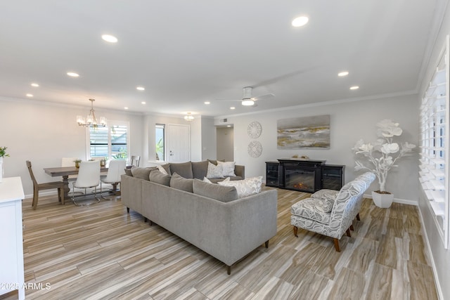 living room featuring ceiling fan with notable chandelier, light hardwood / wood-style flooring, and ornamental molding