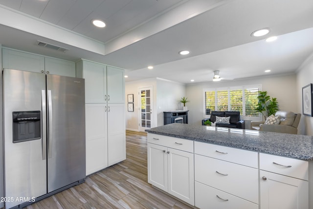 kitchen featuring stainless steel fridge, ornamental molding, dark stone counters, and white cabinets