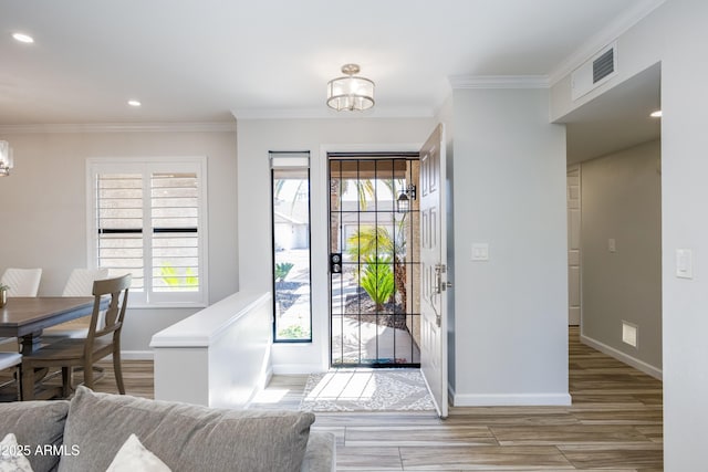 entryway featuring an inviting chandelier, crown molding, and light wood-type flooring