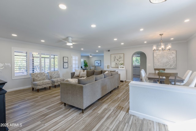 living room with crown molding, ceiling fan with notable chandelier, and light hardwood / wood-style floors