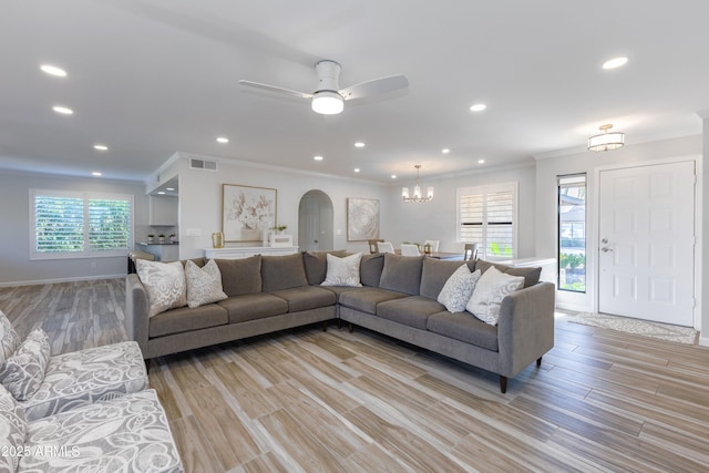 living room featuring crown molding, light hardwood / wood-style flooring, and ceiling fan with notable chandelier