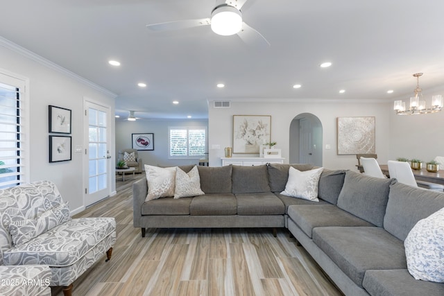 living room with crown molding, ceiling fan with notable chandelier, and light hardwood / wood-style floors