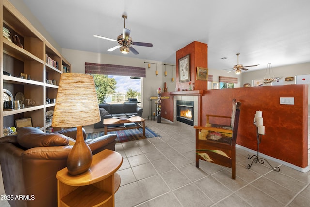 living room with ceiling fan, a tiled fireplace, and light tile patterned floors