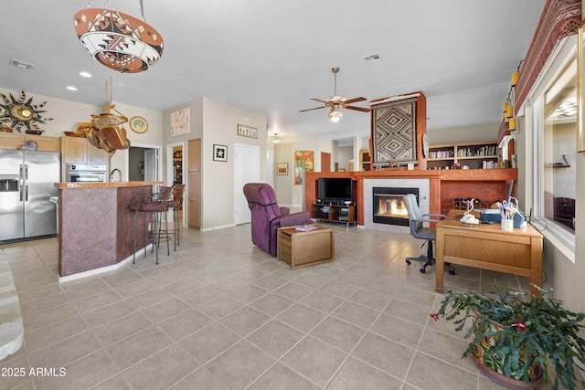 tiled living room featuring sink, a tile fireplace, and ceiling fan